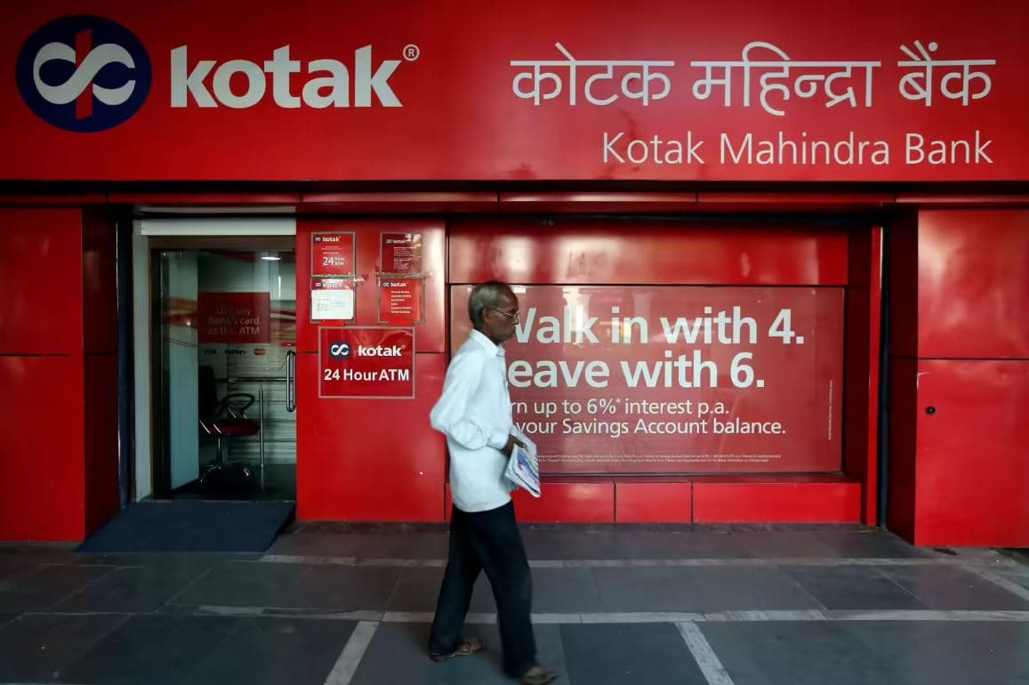 Kotak Mahindra Bank branch exterior with customer walking past signage and ATM facility