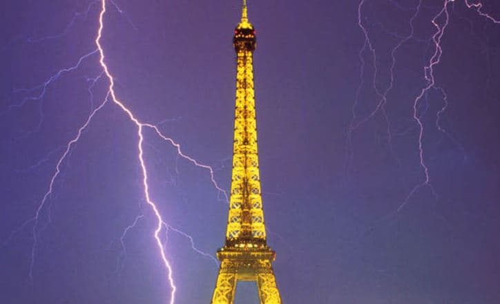 Lightning striking near the illuminated Eiffel Tower during a nighttime thunderstorm in Paris.